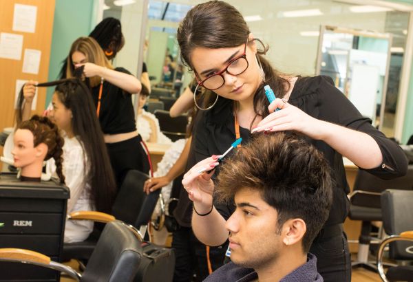 Barbering student cutting her client's hair
