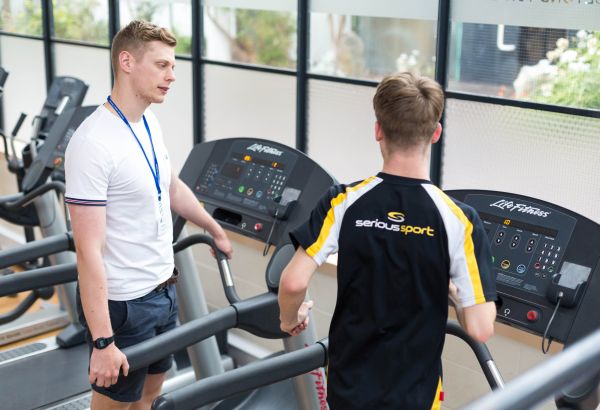 Sport lecturer instructing student on treadmill