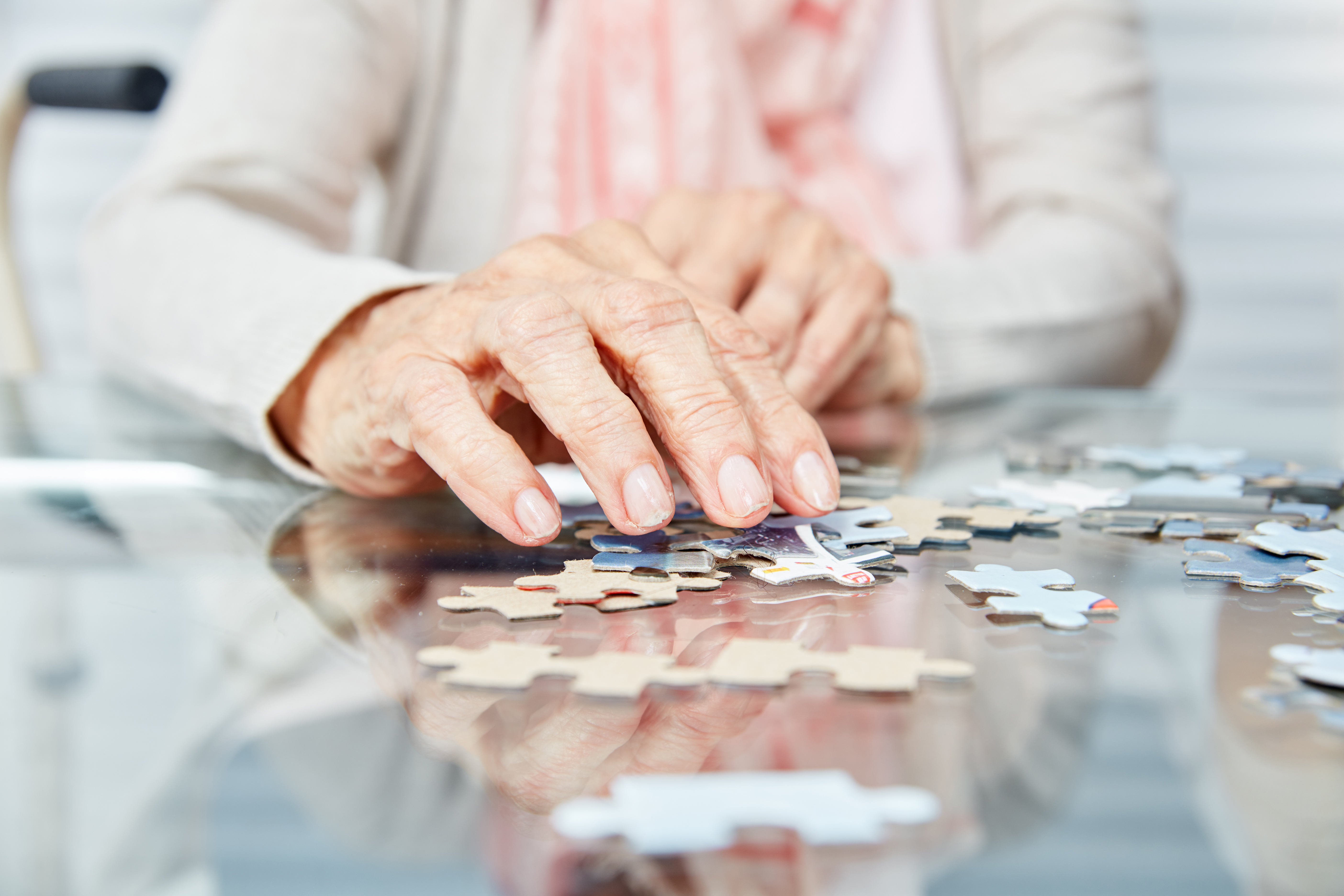 An older person sits completing a puzzle
